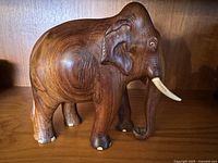 Side view of mahogany elephant carving, showing detailed ear and body carving.