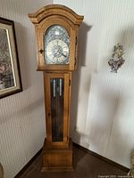 Full view of oak grandfather clock showing entire wooden case and glass front