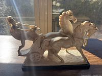 Left side view of white chariot sculpture featuring two horses and soldier on black base