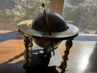 Front view of the brass and wooden globe with visible zodiac ring and wooden base