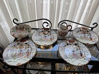 Full set of four porcelain dishes and one cream pitcher arranged on glass table, showing traditional Japanese and floral design.