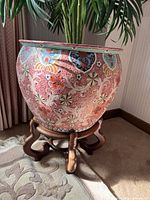 Full view of ceramic planter seated on carved wood stand