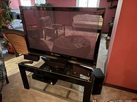 Panasonic 47 inch TV on black glass and metal stand with speakers and DVD player.