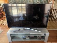 Front view of Samsung TV on matching silver metal and glass stand