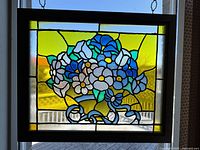 Front view of stained glass window showing full floral design with blue, white, and green glass pieces and yellow background.