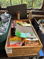 Wooden crate with sanding papers and abrasive disc packs in original packaging showing varying grit types
