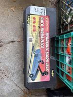 Black plastic case with label showing the image, brand and specifications of the hydraulic floor jack.