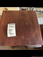 Top view of the wooden claw foot end table showing surface and sticker label.