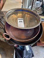 Cast iron pan, copper pan, and silver serving platter stacked