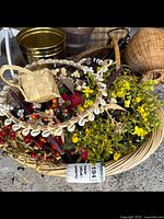 Wicker basket filled with various decorative wreaths and artificial floral elements including yellow flowers and berry-like accents.