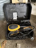 Dewalt corded palm sander inside its open black plastic carrying case. The sander is black and yellow with a cord wrapped around it.