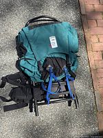 Photo of the teal EMS hiking backpack from front view showing padded shoulder straps, hip belt and external frame