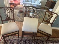 Four cherry finish folding dining chairs with beige cushions arranged in living room setting.