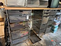 Garage shelving unit showing metal drawers/baskets of various sizes under natural wood top. Shelving is filled with various items to show use.