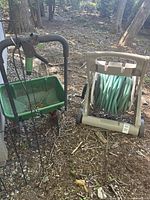 View of green fertilizer spreader with handles and wire plant climber behind it.