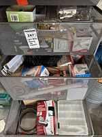 Wide view of metal storage drawers filled with assorted light bulbs, packaging boxes, and plastic storage containers.