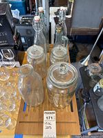 Top-down view of assorted clear glass jars and bottles including swing top and glass lids.