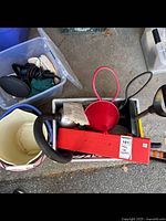 Overview photo showing the red plastic oil funnel, black hose, red road flares, orange shovel handle, and buckets in the background.