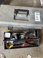 Gray plastic toolbox closed and opened, showing various tools inside.