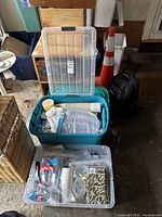 Photo of plastic storage bins containing various party supplies including paper napkins, plastic cups and flatware.