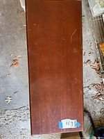 Top view photo of the wooden piano seat showing rectangular flat top surface with wear marks and scratches.