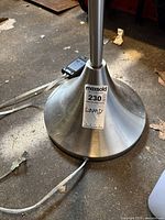 Close-up of brushed silver lamp base with power cord and MaxSold auction tag.