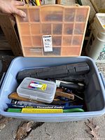 Various hand tools including wrenches, sickle, hatchet, threaded ends, and a power screwdriver stored in plastic bins.