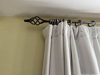 Close-up of decorative finial on curtain rod holding the light gray blackout curtain