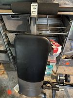 Top view of the workout bench showing padded seat, leg support rollers, and steel frame in a garage setting