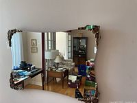 Front view showing the full curved rectangular mirror with ornate metal corner decorations, mounted on the wall.