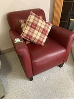 Front view of red leather armchair with two plaid cushions