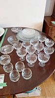 Wide view of Waterford crystal dessert cups, side plates, small bowl, platters and votive glasses displayed on a wooden table