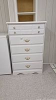 Front view of white five drawer dresser with measuring tag.