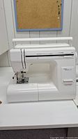 Front view of white Janome sewing machine body with built-in handle extended