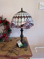 Front view of Tiffany style lamp on painted wood side table with decorative berry vines beside it