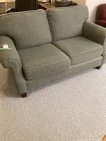 Front view of sage green upholstered loveseat