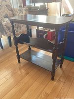 Front view of the vintage three tiered side table showing turned legs and multiple tiers