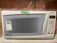 Front view of Panasonic microwave showing model and size label, striped window and Inverter branding.