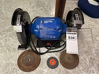 Front view of Power Fist 8 inch bench grinder with two grinding wheels, power cord, and three grinding accessories placed in front.