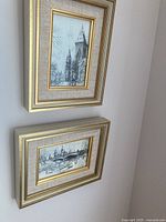 Two framed prints by Edward Brown, one vertical and one horizontal, with gold-tone frames and beige mats hanging on a wall
