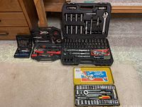 Full view of three tool kits including two ratchet sets and assorted tools