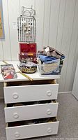 Storage drawers with sewing items, folded fabrics, magazines, and sewing basket on top.