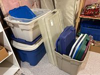 Stack of large beige and blue plastic storage bins with some lids on top and on the side
