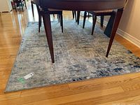 Full view of the area rug under a dining table showing the pattern and size.