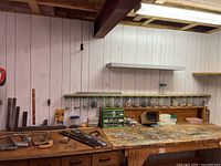Wide view of workbench showing assorted tools, plastic containers, and hardware jars mounted on the wall.