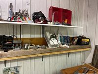 Shelf with assorted hand tools, pliers, wire cutters, tape measures, battery charger, and small hardware items.