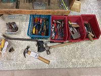 Full view of hand tools in plastic containers and on floor including hammers, wrenches, screwdrivers, staple gun, pliers