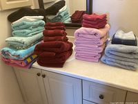 Full overview of assorted towels in various colors and sizes stacked on counter