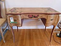 Front view of the wooden vanity desk showing floral painted design and curved legs.