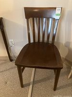 Front view of the wooden chair showing the solid wood seat and slatted backrest.